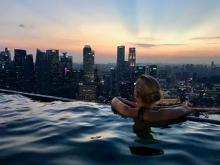 Fototapeten Blond woman in rooftop pool on skyscraper, with skyline in background, Singapore, South East Asia © HWL Photos