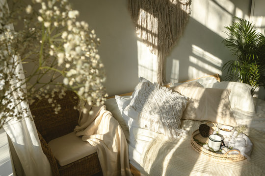 Cozy boho style sunny bedroom with light and shadows and close up of white gypsophila flowers. Authentic real life interior
