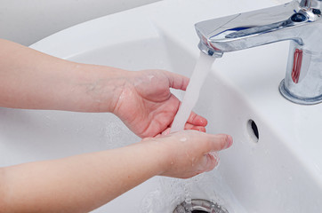 The child washes his hands with soap in the sink under the tap with water. Compliance with...