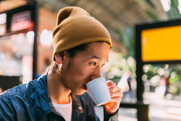 Asian young tourist drinking coffee in the train station