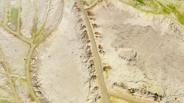 Elevated view photograph of geothermal activity produced thermal spring waters in Egerszalok, Hungary, that sit within colorful textured, terraced limestone formations lined with travertine