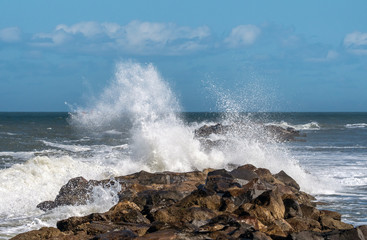 Fototapeta na wymiar Waves breaking over a rock jetty wall.