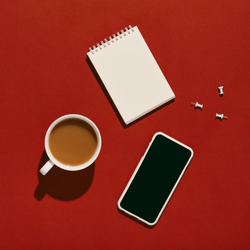 Cellphone on red with notepad, coffee
