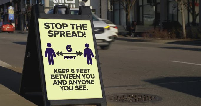 A sign on a sidewalk of a large city warns passers by to stay 2 meters away from each other. Six feet distance became common practice when in public during the coronavirus COVID-19 pandemic of 2020.  
