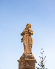 Fototapeta na wymiar Madonna steht auf einem großen Pfeiler auf einem Friedhof in Spanien