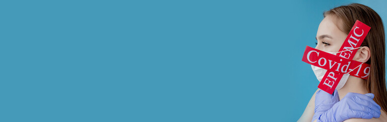 Doctor woman with surgical mask pointing to red paper with mesaage Coronavirus on blue background....