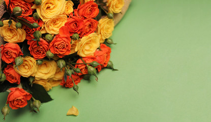 A beautiful, bright bouquet of orange and yellow small flowers-roses on a soft green background, close-up, copying the space.