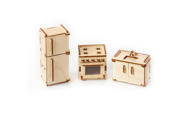 Toy miniature wooden kitchen furniture stands on a white background. Refrigerator, gas stove and sink. Furniture for dolls and dollhouse