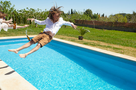 Excited man falling in pool on summer party