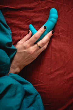 Woman's hand holding a blue sex toy
