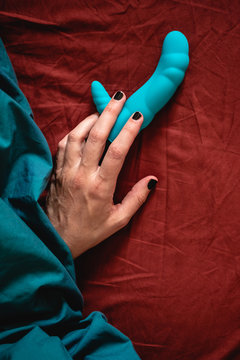 Woman's hand holding a blue sex toy