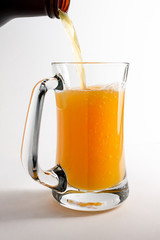 Beer pouring from bottle into mug or stein