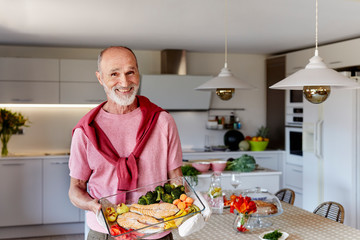 Senior man with the healthy food tray in the kitchen