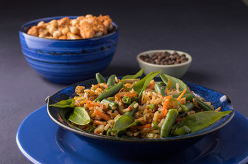 fried rice with vegetables in a blue plate.