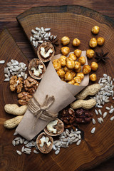 A variety of nuts and seeds on a brown wooden surface. Caramel hazelnuts in the center