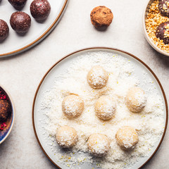 Various Homemade Raw Vegan Truffles or Energy Balls, such as Coconut and Lemon, Almond and Cacao, Dark Chocolate and Hazelnut Butter on Grey Plate and Light Background