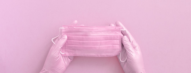 Pink protective surgical face mask and woman hands in gloves background, selective focus, banner