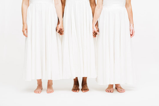 Low section of women holding hands while standing indoors