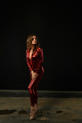 Fototapeta na wymiar sexy girl posing in a red suit on a black background