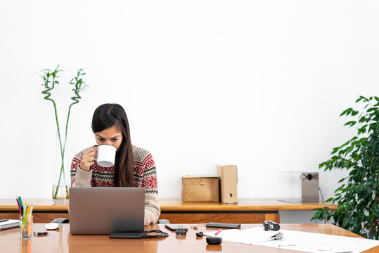 Young Freelancer Working From A Makeshift Home Office Connected To The Internet With A Laptop And A Phone During The Period Of Global Confinement