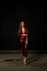 sexy girl posing in a red suit on a black background