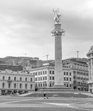 Black and white image of empty Liberty square and statue with no traffic and person in the middle sweeping the street. Tbilisi.Georgia.25.03.2020