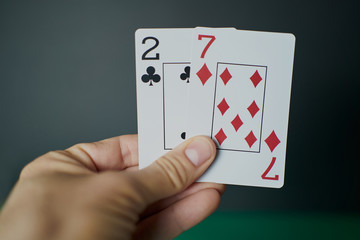 Bad poker gamble or unlucky hand concept with player going all in with 2 and 7 (two and seven) offsuit also called unsuited, considered the worst hand in poker preflop (before the flop is revealed)