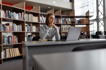 Concentrated woman with laptop in library
