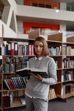 Contemporary student with book in public library