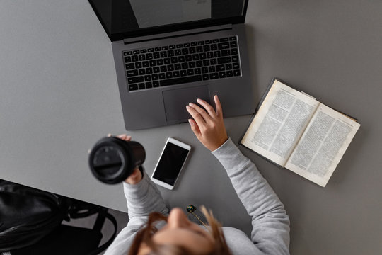 Woman having coffee while studying with laptop