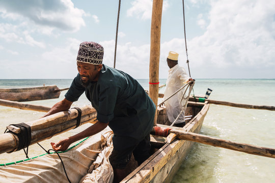 two fishermen prepare to go fishing on the shores of Zanzibar