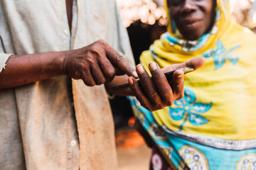 Hands of older man holding a cellphone and a blurred african muslim woman background