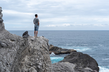 Man looking at the sea from stony coast