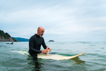 Mid aged man having a beer on a surf table