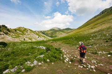 Fototapeta na wymiar Matese Park, Campania, Italy - july 10 2016: a hiker follows the path that leads from Lake Matese to Mount Miletto