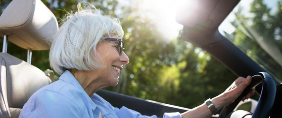Relaxed older woman driving convertable car.