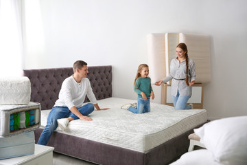 Happy family choosing mattress in furniture store
