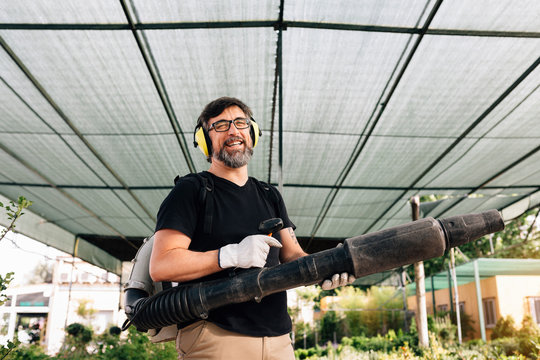 Happy mid adult man posing with a professional blower in the orc