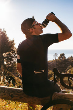 Male Road Cyclist Taking Break and Drinking
