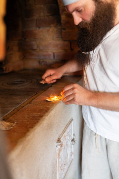 Man lighting match to make fire in oven