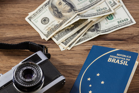 Camera, dinheiro e passaporte sobre mesa de madeira