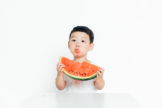 Portrait of cute boy eating watermelon with white background