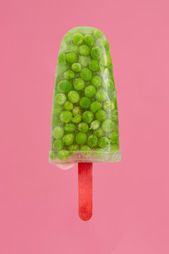 Popsicle made of peas against pink background