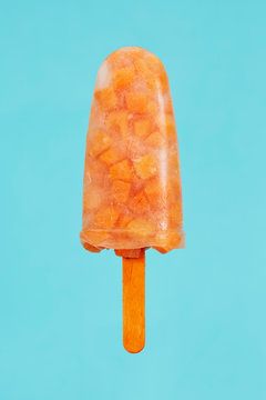 Popsicle made of carrots against blue background