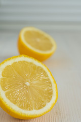 Close-up of two half lemons, with selective focus, on white wooden background and vertical white background with copy space