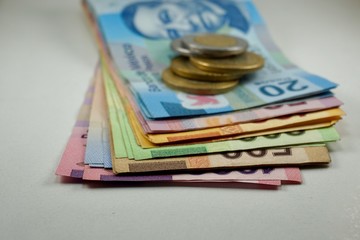 Many mexican pesos bills with coins on top spread over a surface