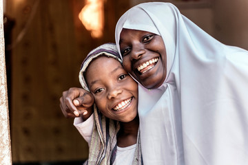 Two girls hugging for the photo, dressed in their school uniform