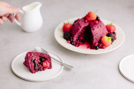 Woman reaches fo cream jug for Summer Pudding dessert