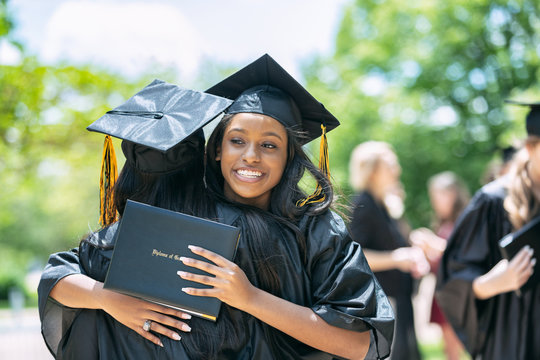 Young women embracing each other after graduation ceremony on campus