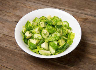 Salad with citrus vinaigrette, avocado cucumber green beans and romaine salad in an bowl on a rustic wooden table. Selected focus.
